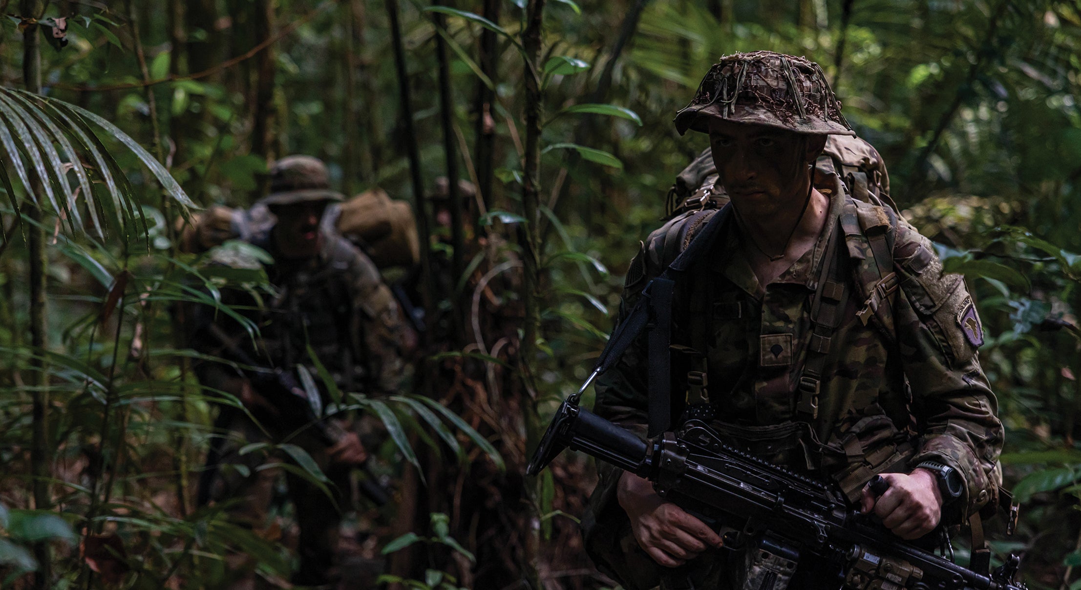 Two U.S. Army soldiers walking through dense jungle