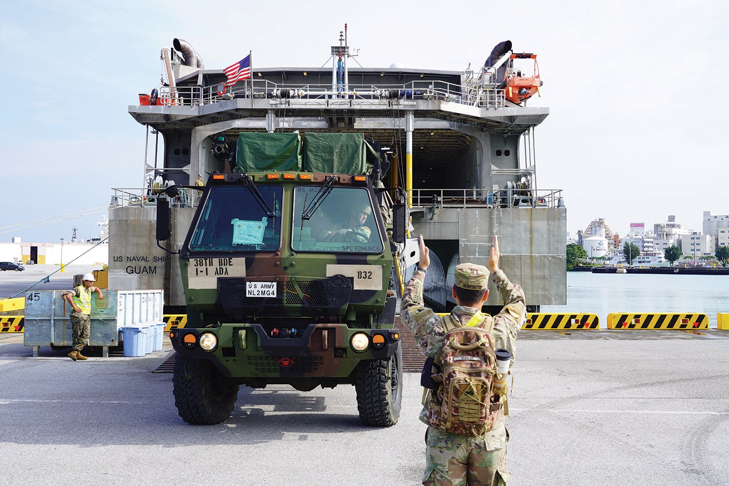 A soldier guides a mobile command center onto a ship at Naha Military Port, Okinawa, Japan. (Credit: U.S. Army/Staff Sgt. Christopher Schmiett)