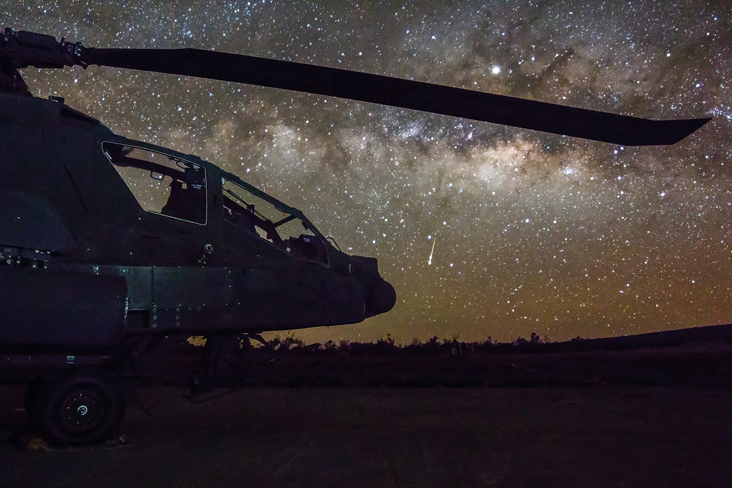 A shooting star serves as the backdrop for an AH-64 Apache attack helicopter on the flight line at Pohakuloa Training Area, Hawaii. (Credit: U.S. Army/Capt. Keith Kraker)