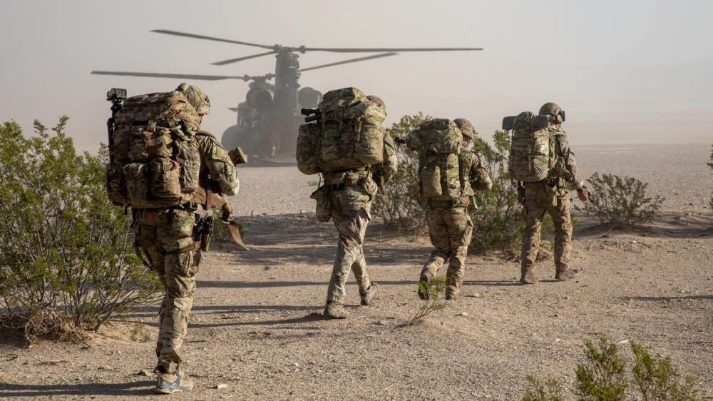 Soldiers with the 7th Special Forces Group (Airborne) and British soldiers with the 4th Rangers move toward a CH-47 Chinook helicopter during Project Convergence 22 at Fort Irwin, California. (Credit: U.S. Army/Spc. Collin MacKown)