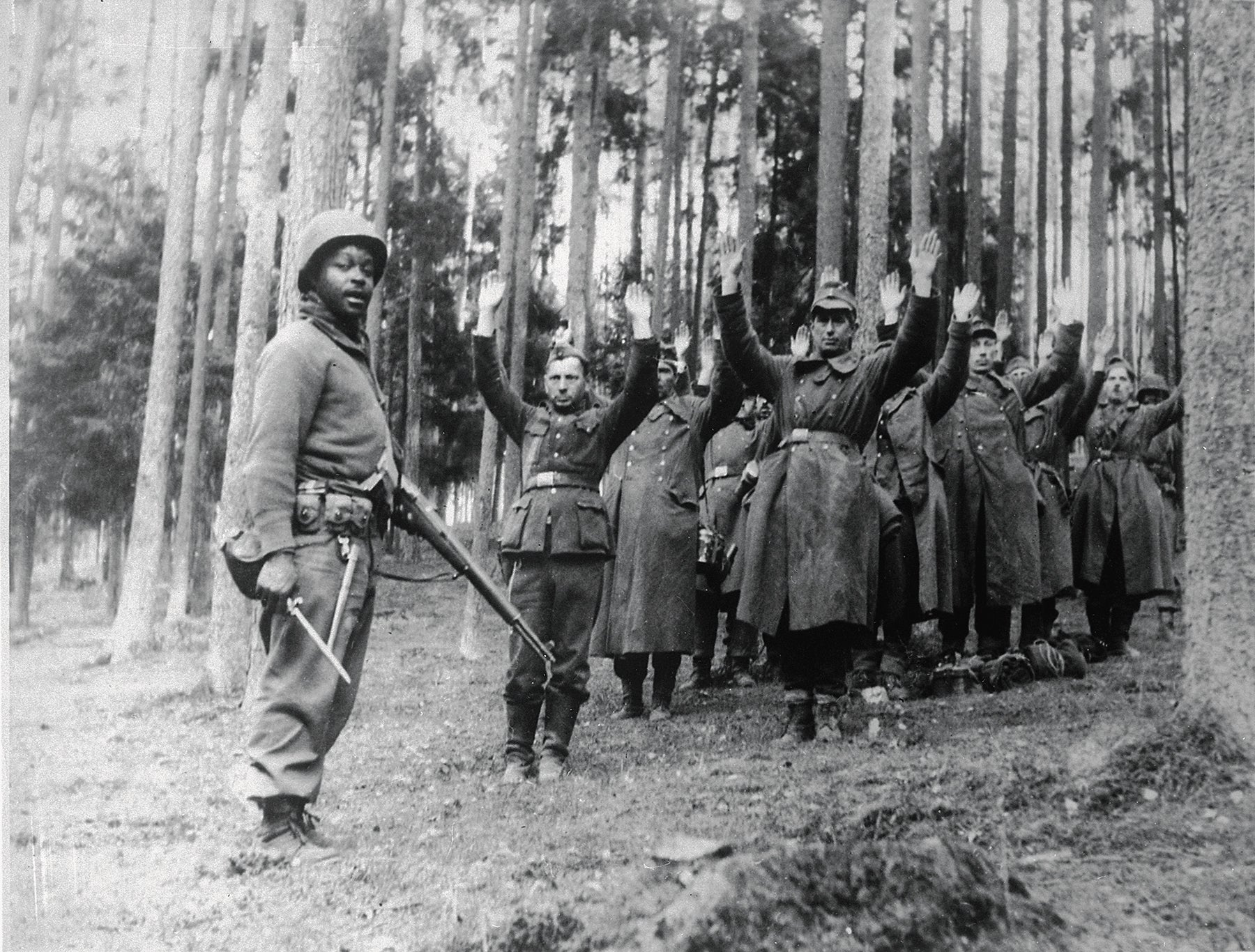 A soldier with the 12th Armored Division guards German prisoners of war in April 1945.