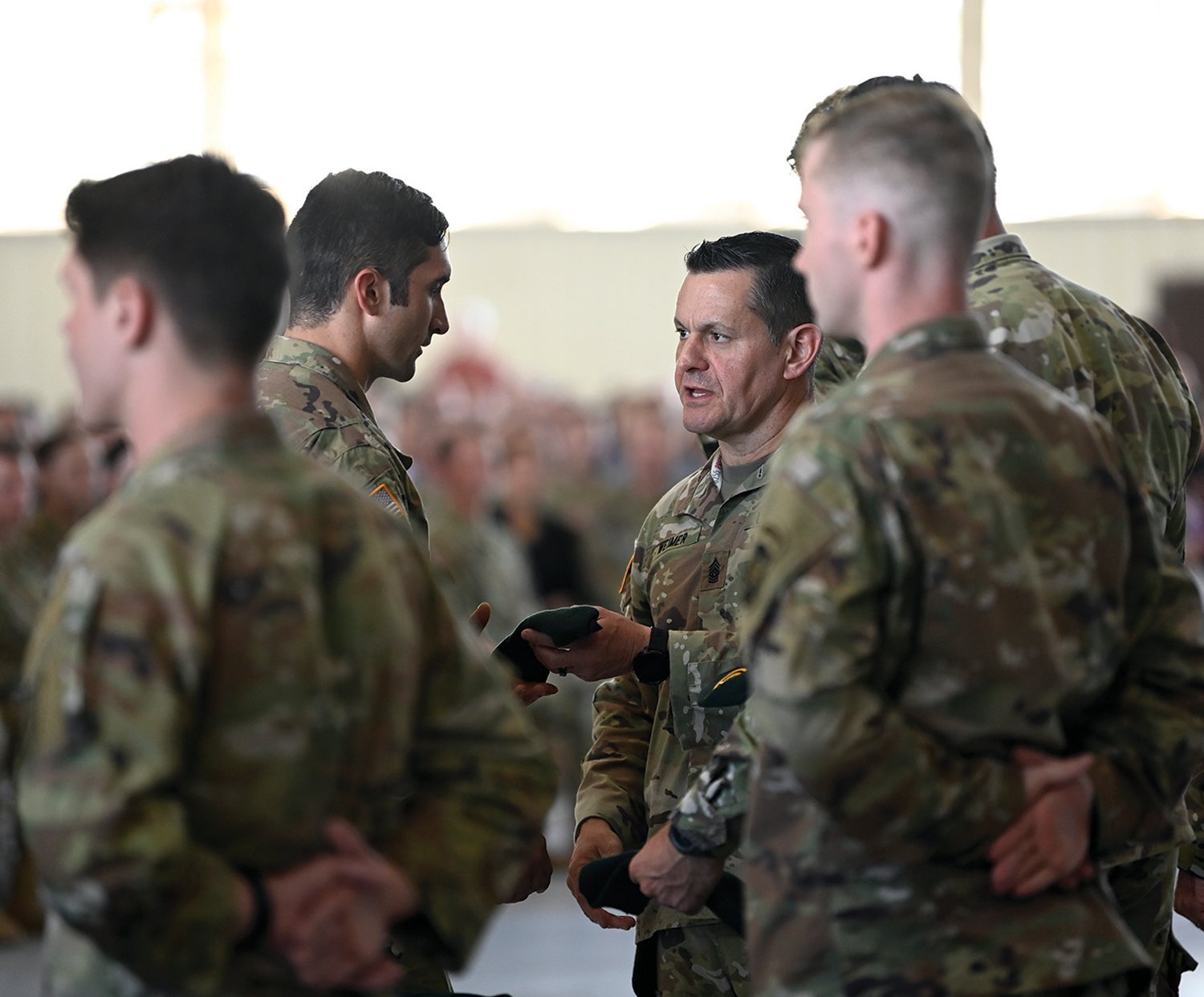 Then-Command Sgt. Maj. Michael Weimer, center right, at that time the senior enlisted leader for the U.S. Army Special Operations Command, presents a green beret to a Special Forces Qualification Course graduate at Fort Bragg, now Fort Liberty, North Carolina. (Credit: U.S. Army/K. Kassens)