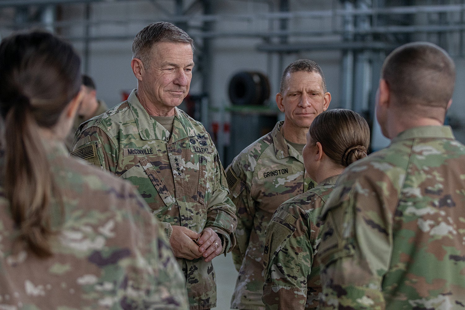 Army Chief of Staff Gen. James McConville, left, and Sgt. Maj. of the Army Michael Grinston, right, recognize a soldier from the 1st Armored Division Combat Aviation Brigade with a challenge coin in Powidz, Poland. (Credit: U.S. Army/Spc. William Thompson)