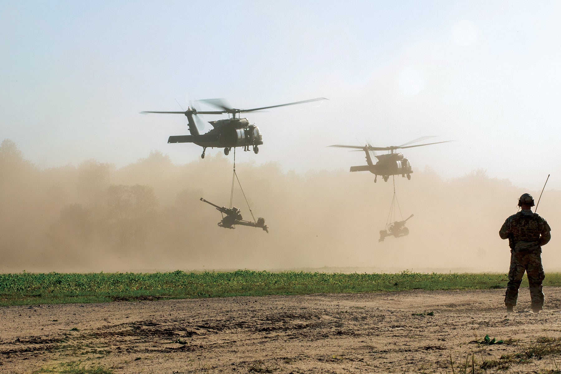 An Ohio Army National Guard soldier observes as UH-60 Black Hawk helicopters bring in howitzers during training at Camp Grayling. (Credit: Ohio Army National Guard/Spc. Olivia Lauer)