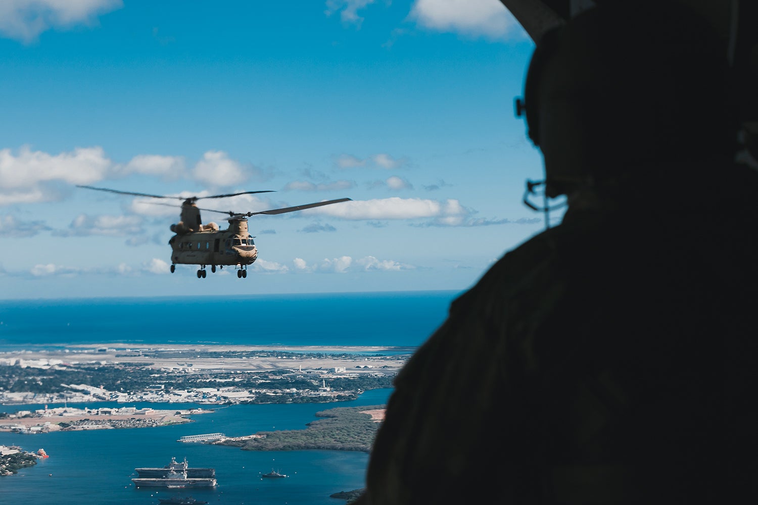 After sailing on the Somervell, soldiers return to Oahu, Hawaii, by helicopter. Here, a crew chief with the 3rd Battalion, 25th Aviation Regiment, looks out at a CH-47 Chinook over Oahu. (Credit: U.S. Army/Spc. Rachel Christensen)