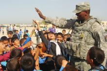 A soldier from the 1st Brigade Combat Team, 10th Mountain Division, plays with a group of children at a school in northern Afghanistan in 2010.